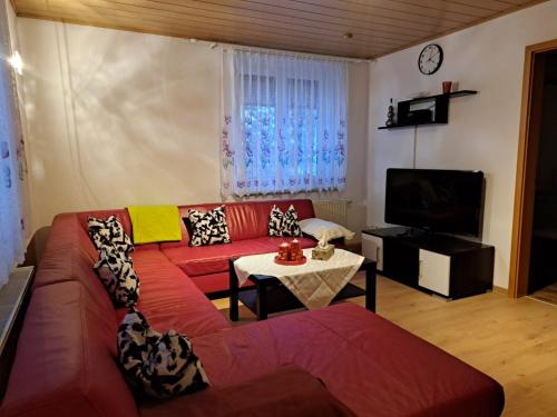 a living room with a red couch and a tv at Ferienwohnung Böhmischerblick in Bärenstein