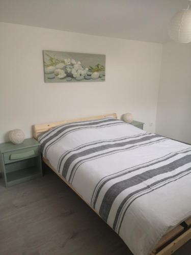 een slaapkamer met een bed en een schilderij aan de muur bij Maison à 500 m du lac in Ardres