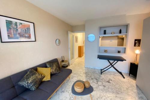 uma sala de estar com um sofá azul e um piano em 06AY - Studio with seafront terrace em Antibes