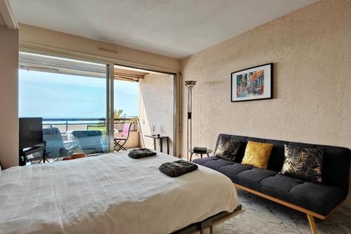 une chambre avec un grand lit et un canapé dans l'établissement 06AY - Studio with seafront terrace, à Antibes