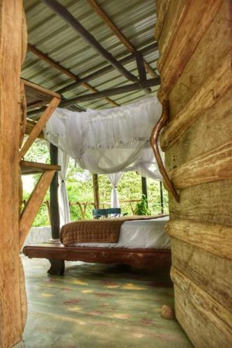 a porch with a bed in a wooden house at Portal del Sol in Villagarzón