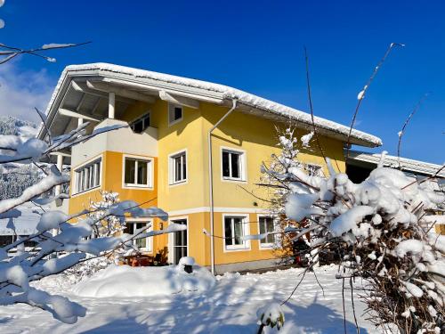a yellow house in the snow with snow covered trees at Appartement Christine in Sankt Johann im Pongau