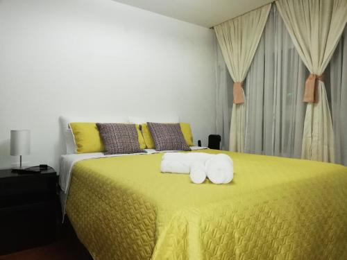 Un dormitorio con una cama amarilla con toallas. en Apto. acogedor cerca de todo lo mejor de la ciudad, en Manizales