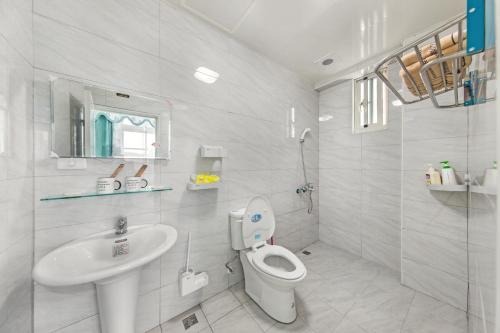 ein weißes Bad mit einem WC und einem Waschbecken in der Unterkunft XICHI Homestay in Jinning