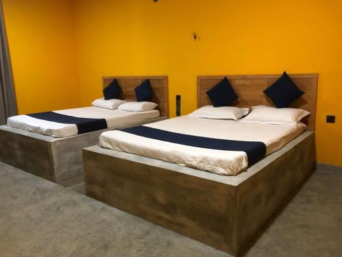 2 camas grandes en una habitación con paredes amarillas en Palabaddala Tea and Eco Lodge en Ratnapura