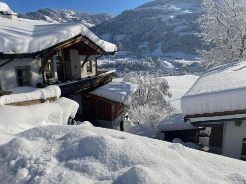 a house covered in snow with mountains in the background at Residenz am Berg in Jochberg