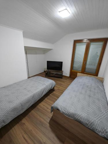 a bedroom with two beds and a flat screen tv at Appartement proche du centre in Thonon-les-Bains