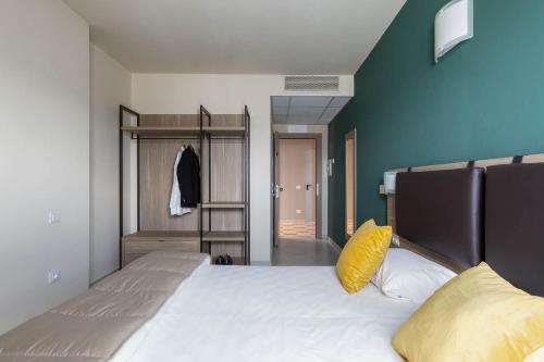 a bedroom with a bed with a yellow pillow on it at Tuscasì Aparthotel in Sovicille