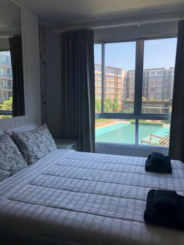 a bedroom with a large bed and a large window at Baan Thewlom in Cha Am