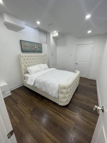 a white bed in a bedroom with a wooden floor at luxury & Spacious 2 bedrooms basement serviced apartment in Brampton
