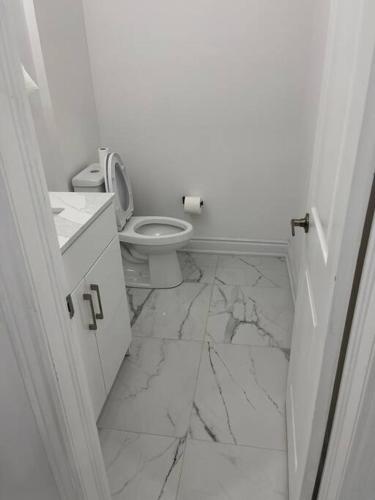 a white bathroom with a toilet and marble floor at luxury & Spacious 2 bedrooms basement serviced apartment in Brampton