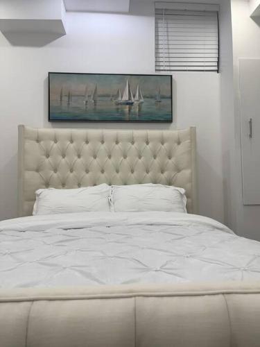 a bedroom with a white bed and a painting of a boat at luxury & Spacious 2 bedrooms basement serviced apartment in Brampton
