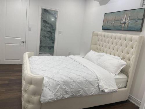 a bedroom with a white bed with a white comforter at luxury & Spacious 2 bedrooms basement serviced apartment in Brampton