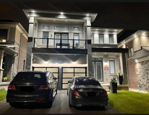 twee auto's geparkeerd voor een huis 's nachts bij luxury & Spacious 2 bedrooms serviced apartment in Brampton