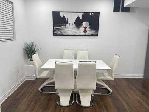 a white dining room with a white table and chairs at luxury & Spacious 2 bedrooms basement serviced apartment in Brampton