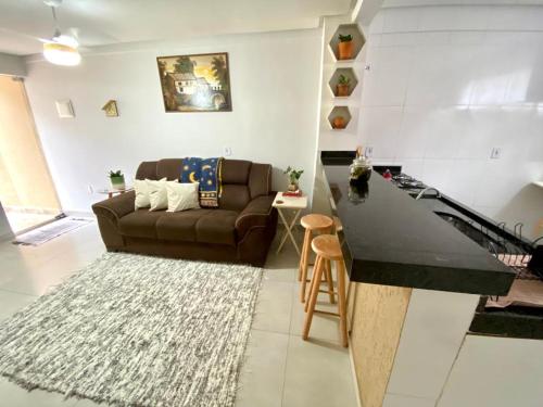 a living room with a brown couch and a kitchen at Refugio Urbano in Goiânia