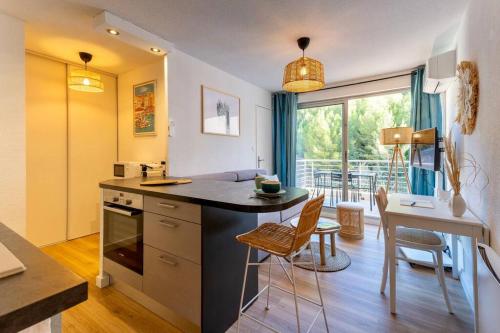 a kitchen with a counter and a table and chairs at Appartement rénové, calme et proche des plages. in Sète