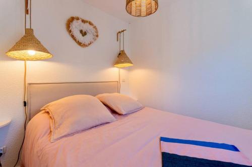 1 dormitorio con 1 cama blanca y 2 lámparas en Appartement rénové, calme et proche des plages., en Sète