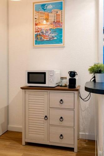 a microwave sitting on top of a dresser in a room at Appartement rénové, calme et proche des plages. in Sète
