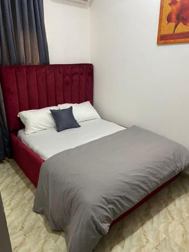 a bed with a red headboard in a room at Excel suite by Home Glides in Lekki