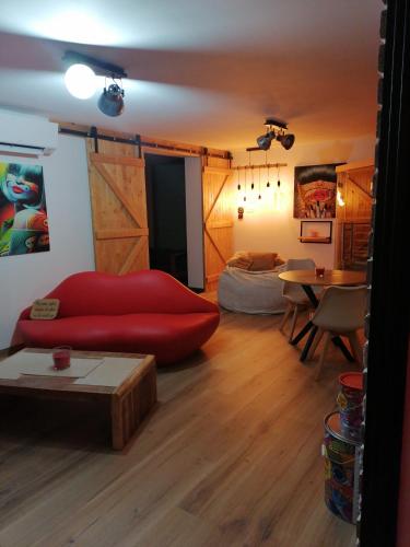 a living room with a red couch and a table at Gîtes déco pop et chaleureuse avec jacuzzi, sauna, piece coquine in Calais