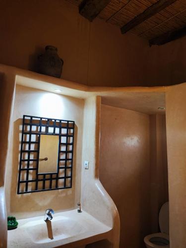 a bathroom with a sink and a mirror and a toilet at Hôte sahara & spa TADIGHOUST in El Hara