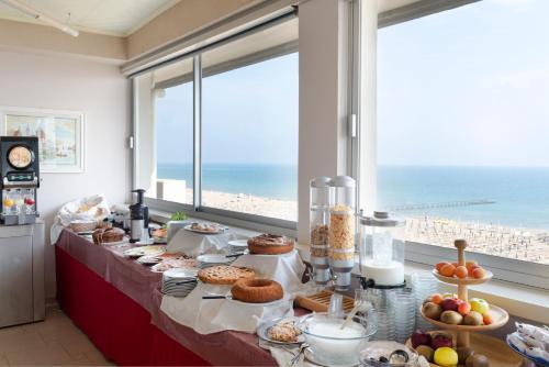 un tavolo con cibo sopra con vista sulla spiaggia di Hotel Centrale Miramare a Rimini