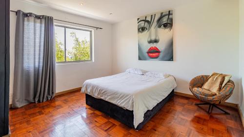 een slaapkamer met een bed en een schilderij van een vrouw bij The View in Kaapstad