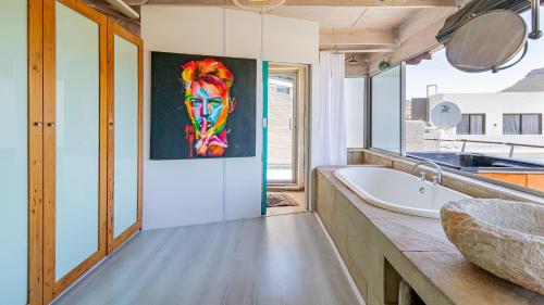 een badkamer met een bad en een schilderij aan de muur bij The View in Kaapstad