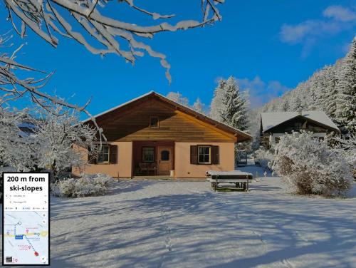 a cabin in the snow with a bench in front at Lussuoso Chalet in centro a 4 min a piedi dalle piste da sci in Tarvisio