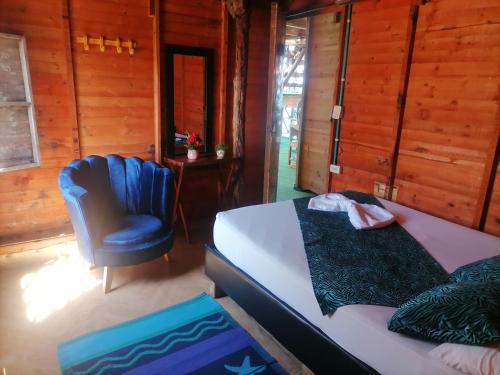 a bedroom with a bed and a blue chair at Posada chikiluky beach in Playa Blanca
