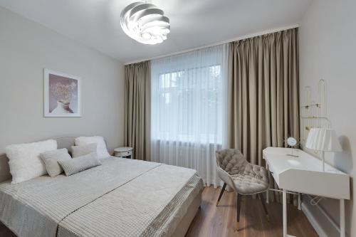 biała sypialnia z łóżkiem, biurkiem i umywalką w obiekcie Central Luxury Apartments w mieście Jełgawa