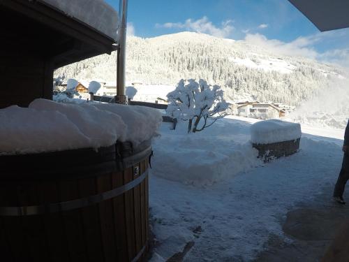 a barrel covered in snow next to a mountain at Ferienhaus Bergauf with Hot Tub in Neukirchen am Großvenediger
