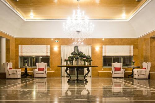 a lobby with a table and chairs and a chandelier at Bella Beach Hotel in Hersonissos