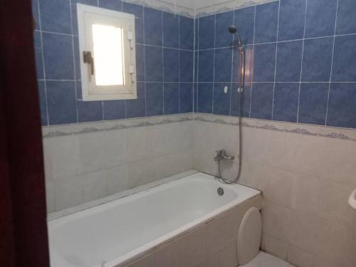 a bathroom with a tub and a toilet and a window at Chambre Chez Jean in Nouakchott
