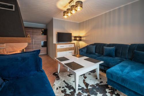 a living room with a blue couch and a table at Zielony Zakątek Karpacz Apartamenty in Karpacz