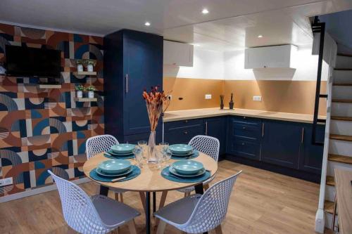una cocina con armarios azules y una mesa con sillas en Maison de village, en Chirac