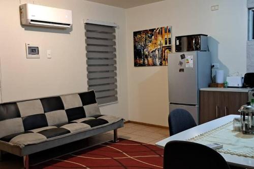 sala de estar con sofá, mesa y nevera en Cómodo departamento full equipado en Coyhaique, en Coyhaique