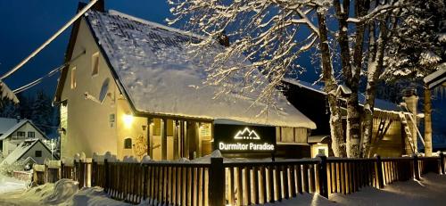 a building with a sign on it in the snow at Guest House Durmitor Paradise in Žabljak