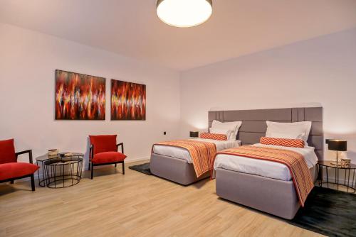 a bedroom with two beds and two chairs and a painting at Villas Lucy - 1 Lemon -outdoor pool , 2 Cherry-indoor pool and 3 Plum-outdoor pool in Marina