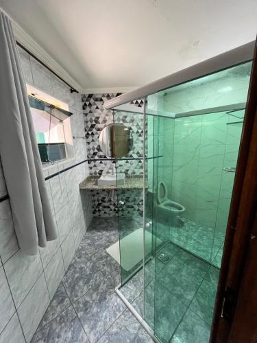 a bathroom with a glass shower with a toilet at Pousada Elegance Beira Mar in Itanhaém