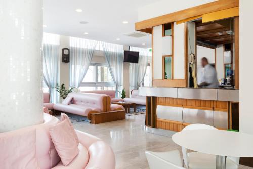 a living room with pink furniture and a man in the mirror at Hotel Centrale Miramare in Rimini