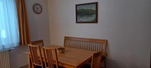 einen Esstisch mit Stühlen und eine Uhr an der Wand in der Unterkunft Ferienwohnung by Pfleger's in Ulrichsberg