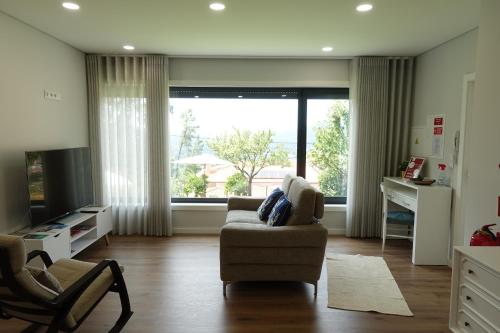 a living room with a chair and a large window at Montinho 313 in Arouca