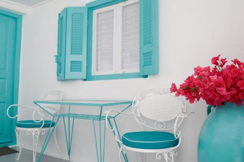 a table and two chairs and a vase with flowers at The Turquoise House in the heart of Ioulida, on the island of Kea. in Ioulis