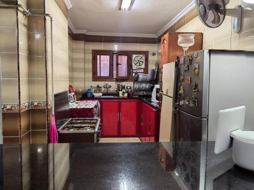 una pequeña cocina con armarios rojos y nevera. en Sanctuary, en El Cairo