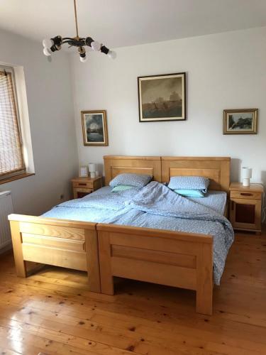 a bedroom with a large wooden bed with blue sheets at Garden's apartman - Kosjerić in Kosjerić