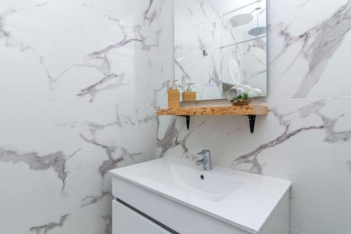 La salle de bains blanche est pourvue d'un lavabo et d'un miroir. dans l'établissement Gyula Old Town Apartment, à Albufeira