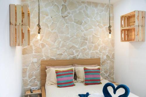 Cette chambre comprend un lit avec deux oreillers et un mur en pierre. dans l'établissement Gyula Old Town Apartment, à Albufeira
