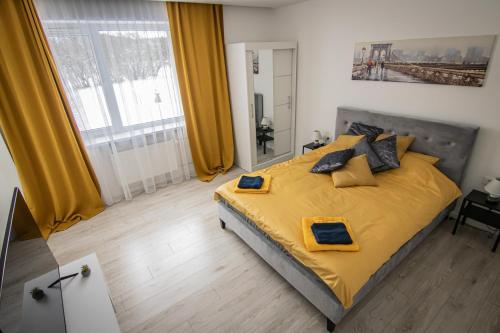 1 dormitorio con 1 cama grande con sábanas y almohadas amarillas en Ramūs apartamentai, en Anykščiai